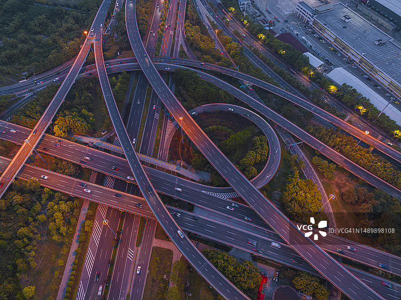 黄昏时繁忙的十字路口鸟瞰图，立交桥和夜间城市交通图片素材