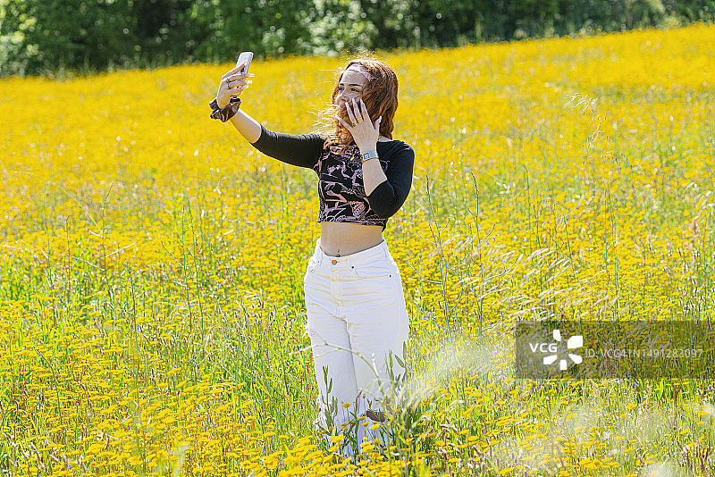 一名女子在盛开的黄色雏菊地里自拍图片素材
