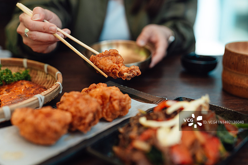 一名女性在餐厅用筷子吃韩国炸鸡的剪影图片素材