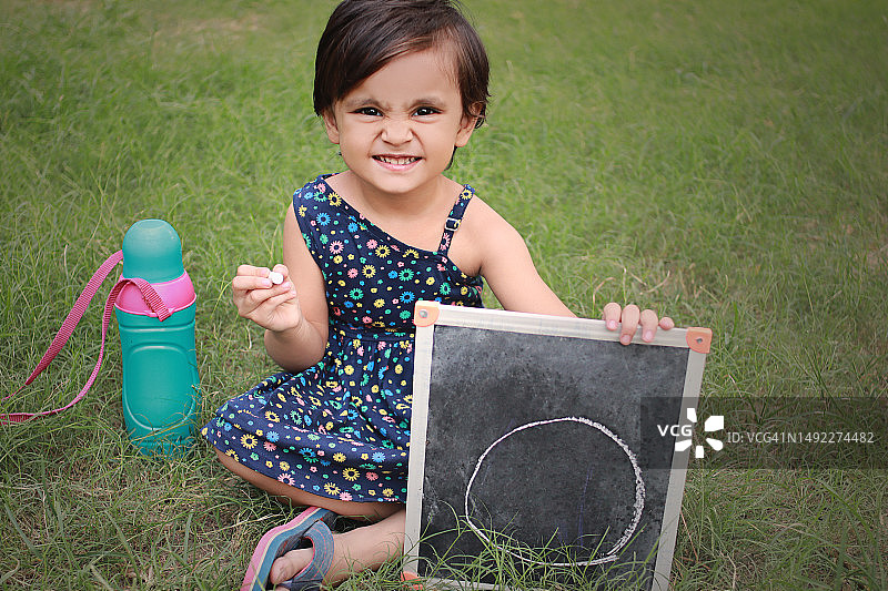 欢快的女婴在黑板上展示着大大的零图片素材