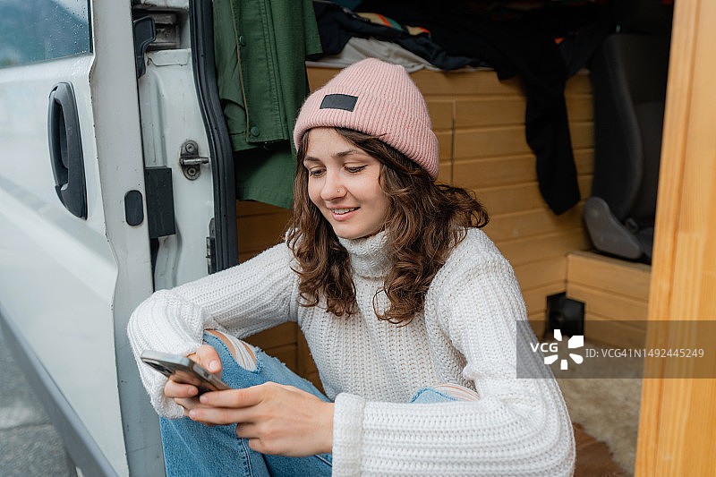 坐在露营车里玩智能手机的女人图片素材