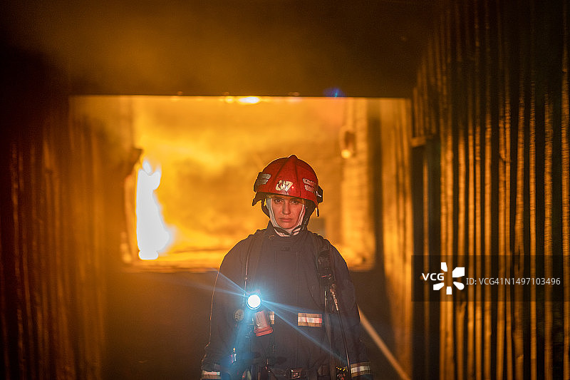 女消防员在火灾背景下的照片。图片素材