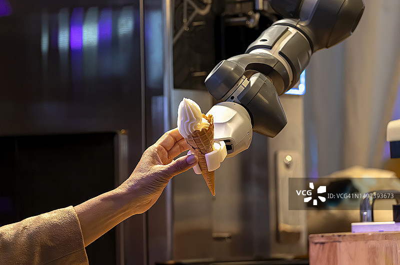 机器人手臂在咖啡馆准备冰淇淋甜筒图片素材