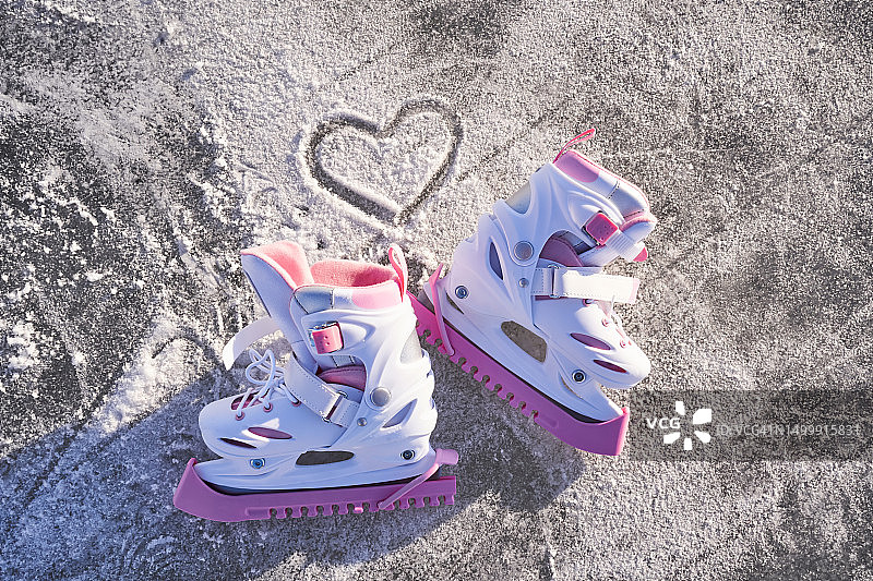 滑冰靴在冰上，在溜冰场上画着一颗心。图片素材