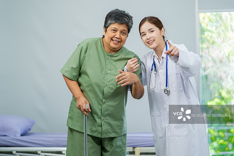 亚洲女医生在护理医院帮助老年残疾妇女用助行器行走。图片素材
