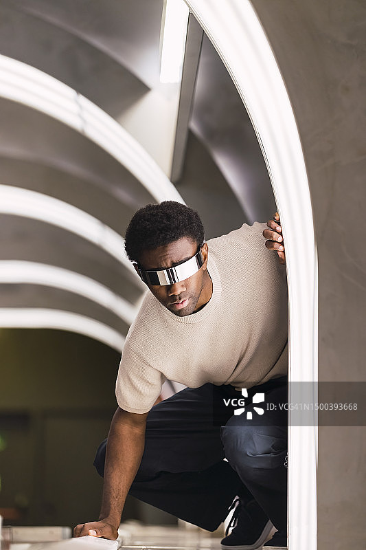 戴着网络眼镜的未来派男子蹲在地铁隧道里图片素材