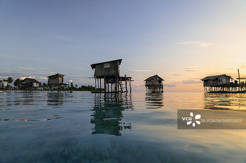 海上吉普赛人的高跷房屋在宁静的日出期间的海水图片素材