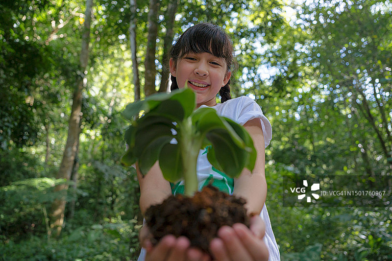 防止全球变暖，女孩种一棵小树。图片素材