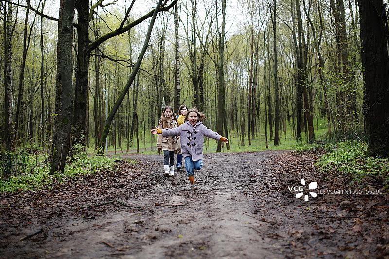 探索大自然的奇迹:加入孩子们在春林的土路上奔跑的愉快旅程，他们灿烂的笑容捕捉了快乐和好奇的本质。图片素材