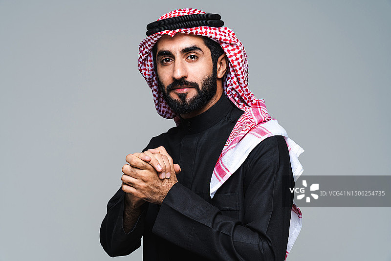 身穿传统服装的男子站在灰色背景下的画像，摄于阿拉伯联合酋长国图片素材