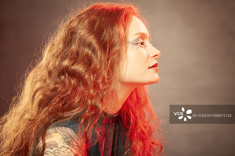 一个年轻漂亮的红发女人的艺术肖像，她的妆容很有艺术感。使用的光效图片素材