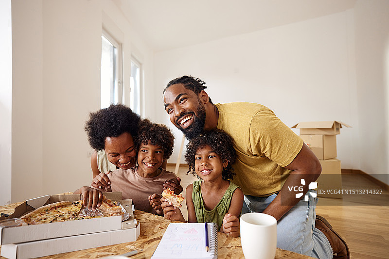 快乐的黑人家庭在搬到新家后吃着披萨玩得很开心。图片素材