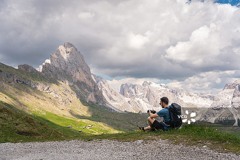 一名白人男子在徒步旅行中休息，用相机拍摄白云石的美景图片素材