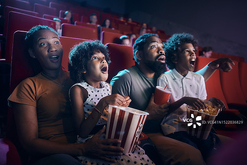 震惊的黑人家庭在电影院看电影。图片素材