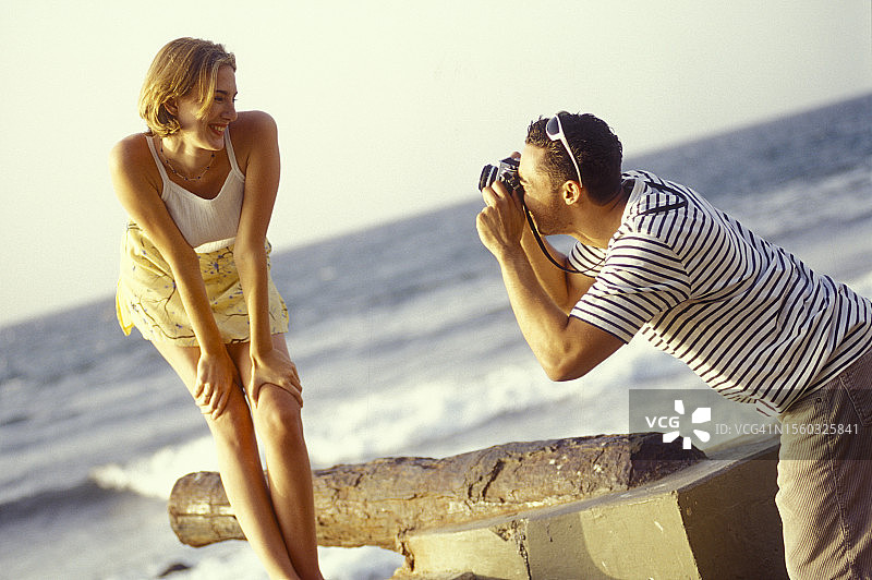 一个男人在海滩上给他女朋友拍照图片素材