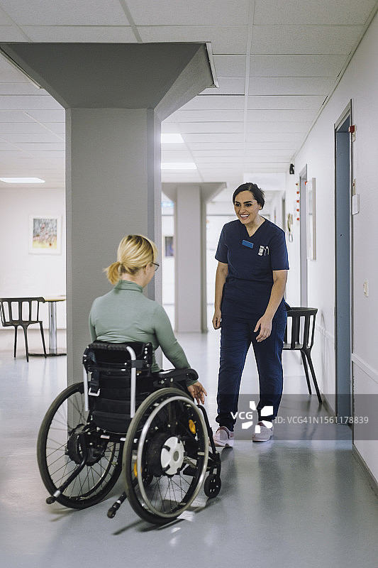 微笑的女医护人员走向医院的残疾病人图片素材