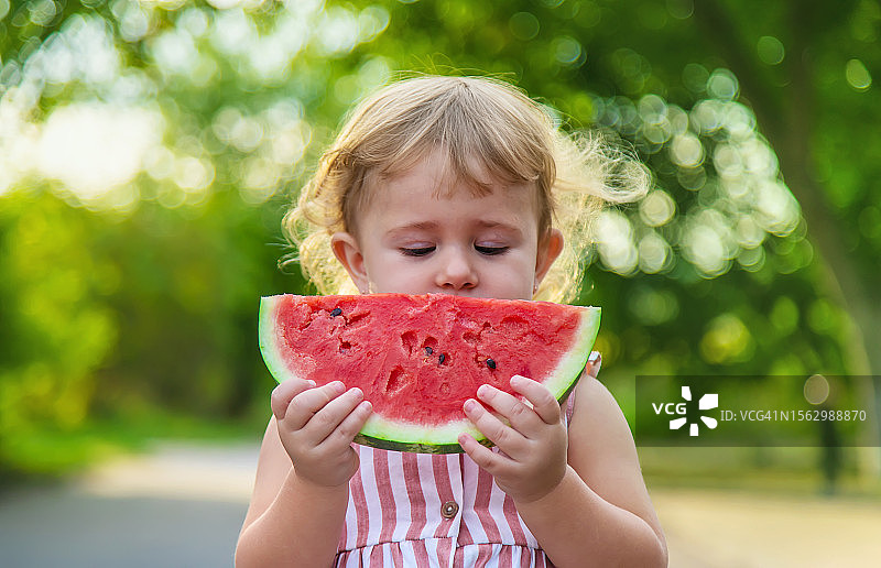 小女孩在夏天吃西瓜。有选择性的重点。图片素材