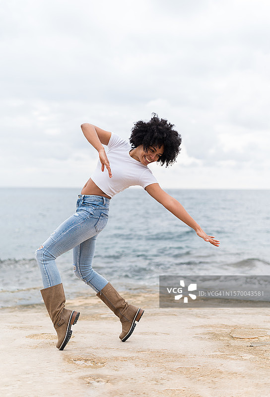 一个非洲女人在沙滩上跳舞的垂直照片图片素材