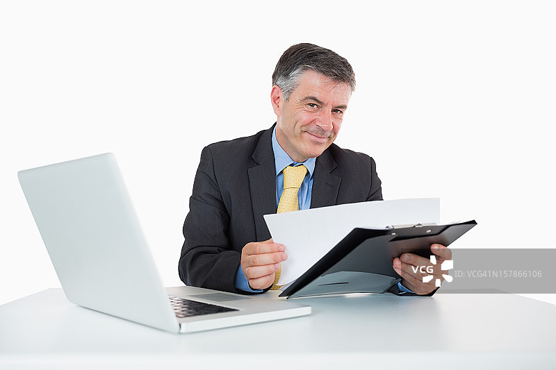 微笑的男人在他的桌子上阅读文件图片素材