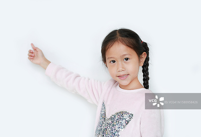 可爱的小女孩伸出食指，在白色的背景上呈现出孤立的东西。教育观念中的亚洲女学生。图片素材