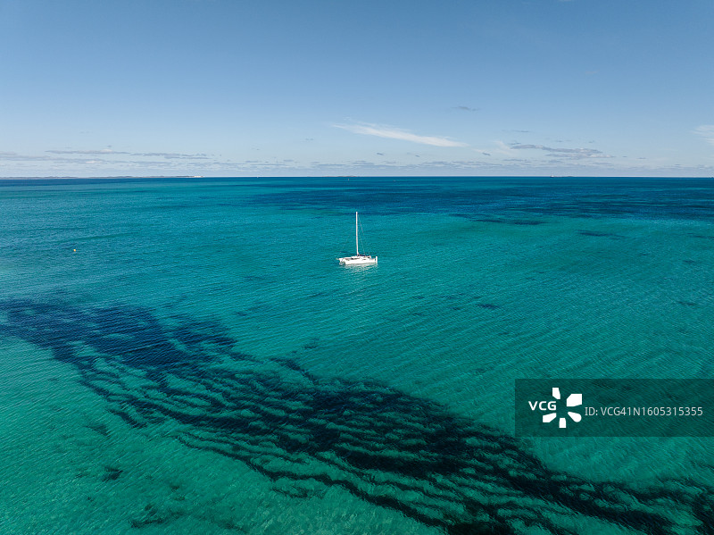 航拍照片显示一艘游艇在一个阳光明媚的日子里航行在大洋上，珀斯，西澳大利亚，澳大利亚图片素材