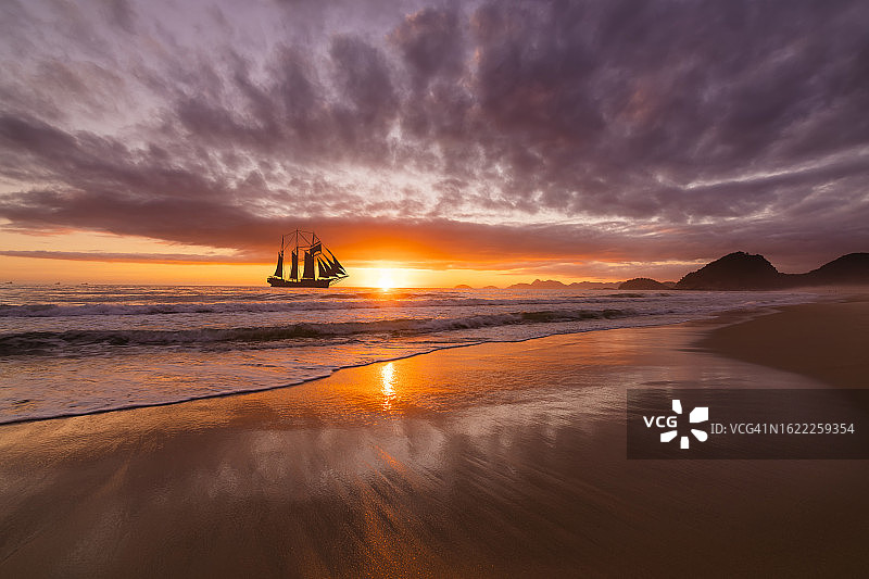 热带岛屿海岸附近日落时的帆船图片素材