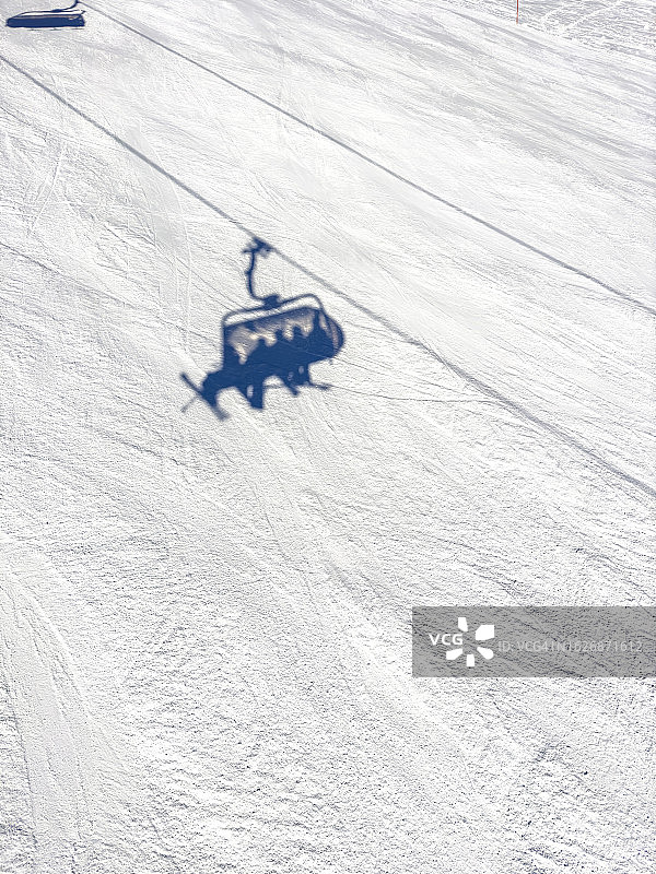 白雪覆盖的景观特写。地面上滑雪缆车的影子。轮廓。图片素材