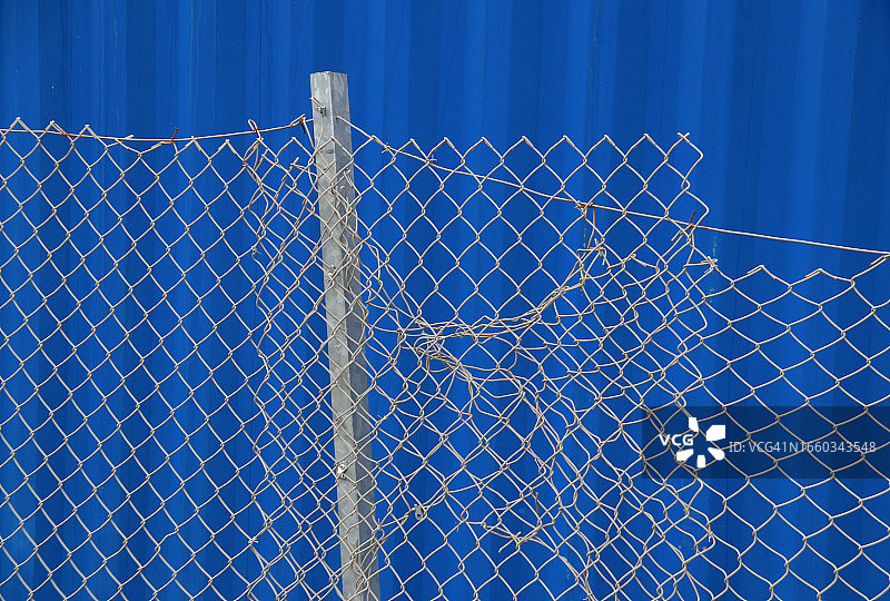镀锌的铁链栅栏和柱子，背景是蓝色的货箱图片素材