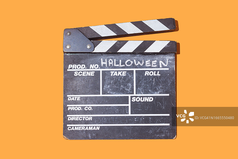 木制的电影院板上用粉笔写着“万圣节”，背景是橙色的。电影的概念，电影，万圣节，庆祝，电影摄影，恐惧和庆祝。图片素材