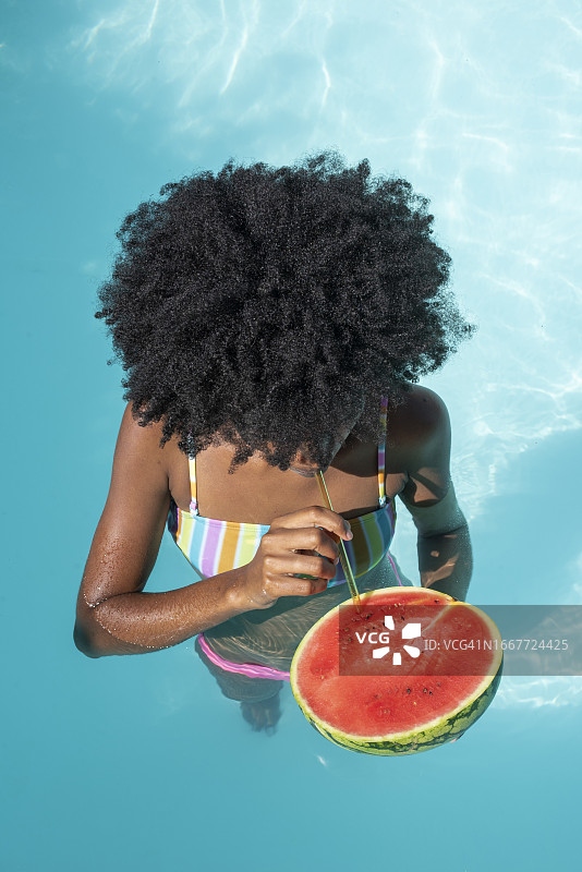 女子在泳池里喝西瓜汁图片素材