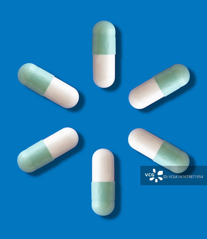 药物胶囊和药丸在蓝色背景和一个小阴影上形成一个圆圈。图片素材