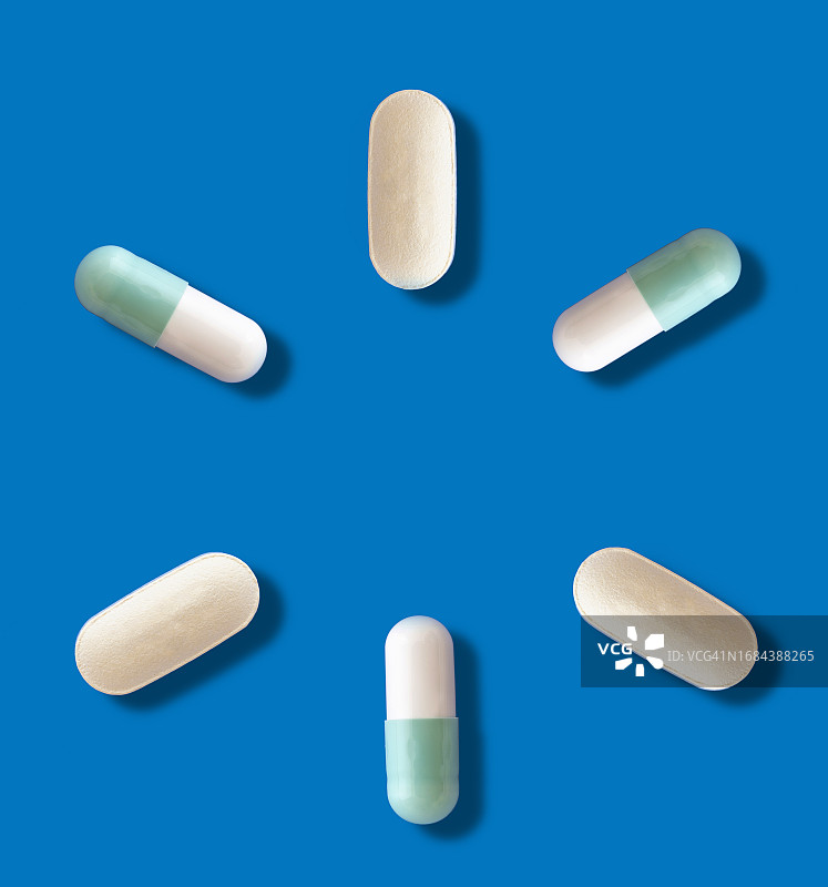 药物以药丸的形式出现在蓝色背景和一个小阴影上。图片素材