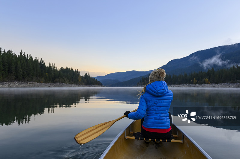 女子在美丽的山间湖泊上划独木舟图片素材
