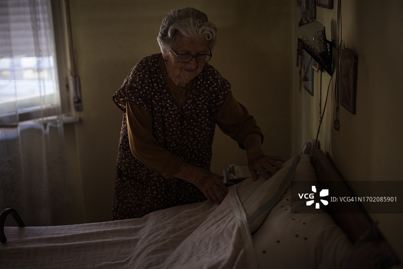 一位年长的女士正在整理她的卧室图片素材