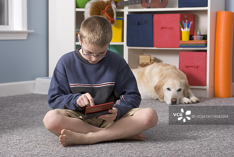 小男孩在和狗狗玩电子游戏图片素材