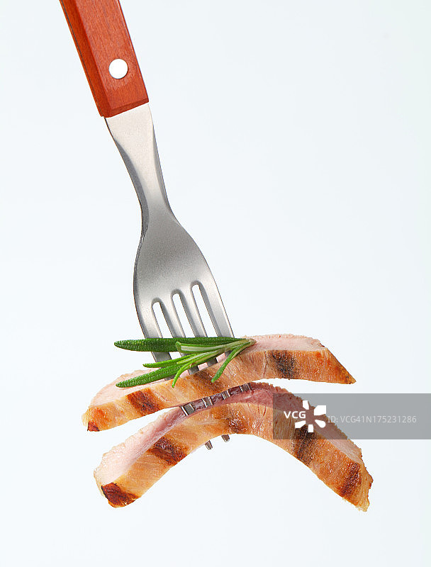 用叉子叉上百里香的半熟猪肉片图片素材