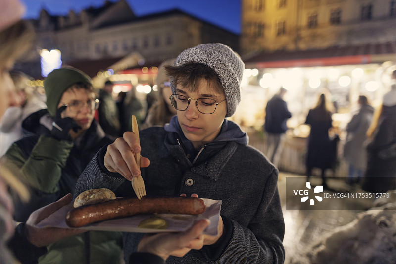 波兰克拉科夫，十几岁的孩子们在圣诞市场上吃街头小吃图片素材