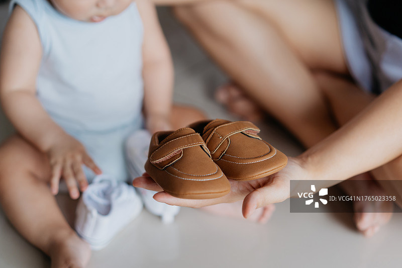 年轻的母亲帮助婴儿试穿新鞋图片素材