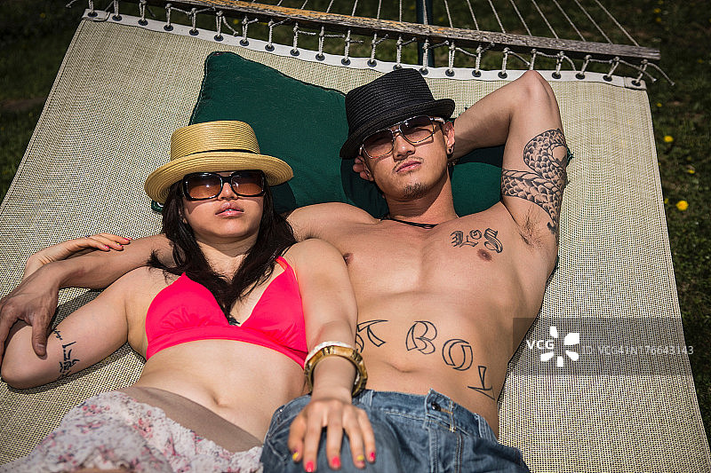 一对夫妇戴着帽子和太阳镜躺在吊床上图片素材