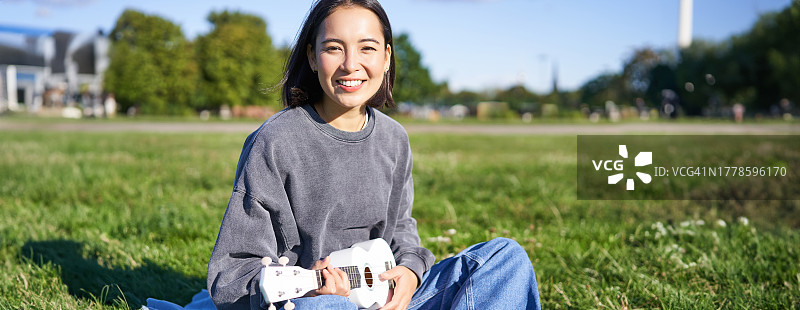 一个微笑的年轻女子坐在草地上的肖像图片素材