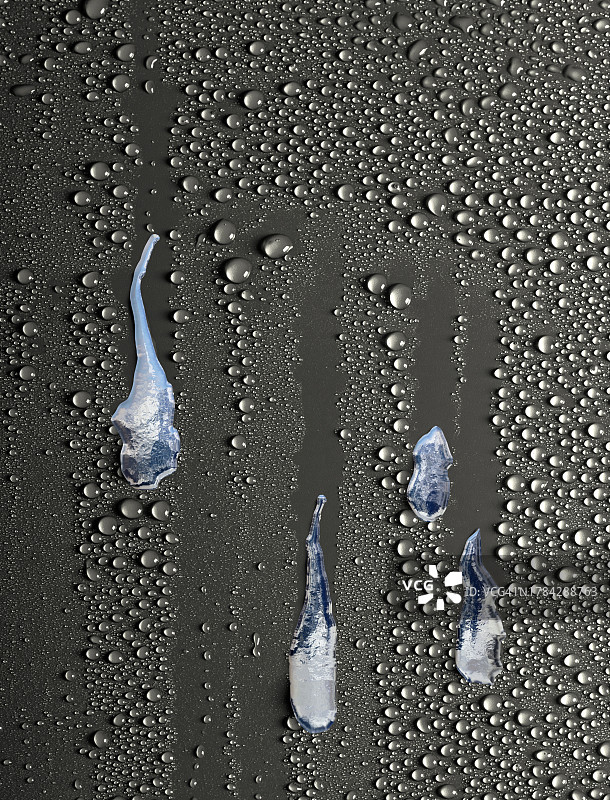 透明的水滴滑下潮湿的灰色背景。图片素材