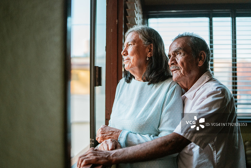 一对老年夫妇在家里透过窗户沉思图片素材