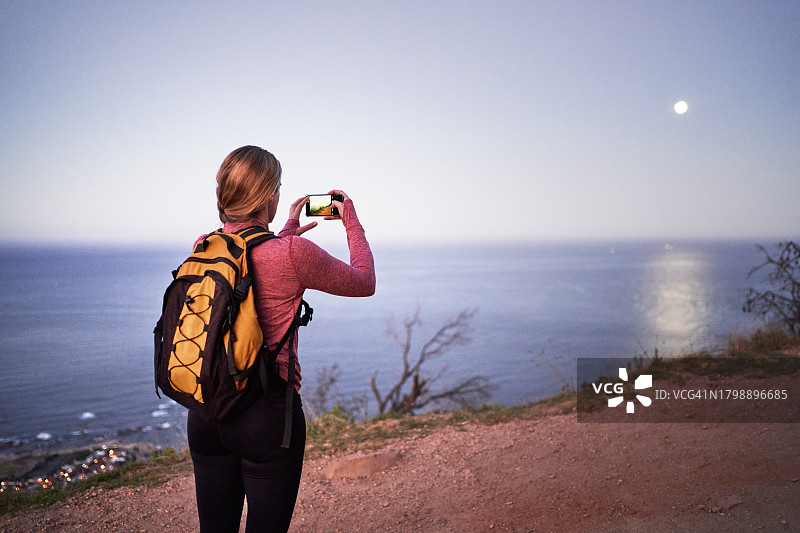 女徒步旅行者用智能手机拍摄海景图片素材