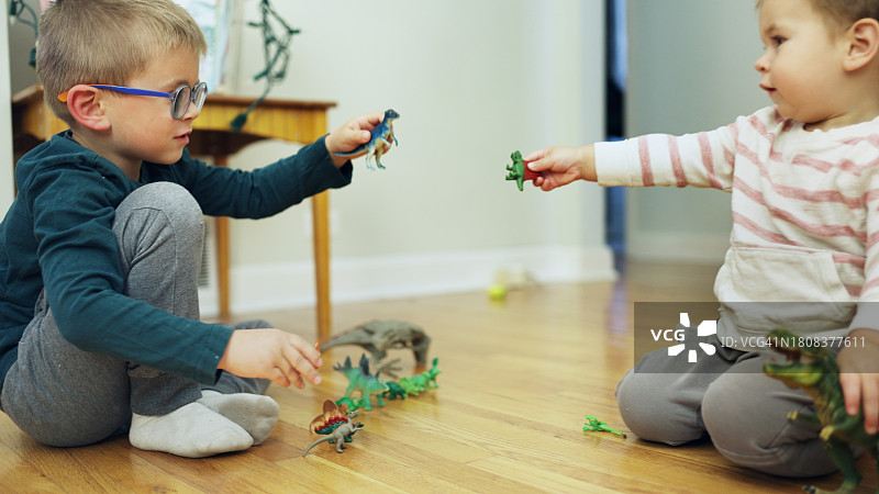 弟弟们在客厅的地板上玩玩具恐龙图片素材