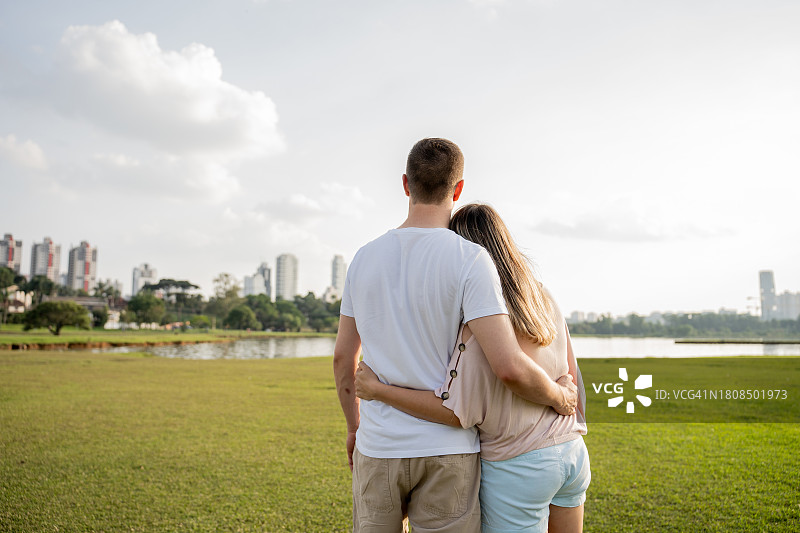 年轻夫妇在公园拥抱看日落图片素材