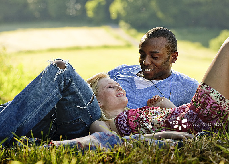 一对浪漫的年轻夫妇躺在草地上图片素材