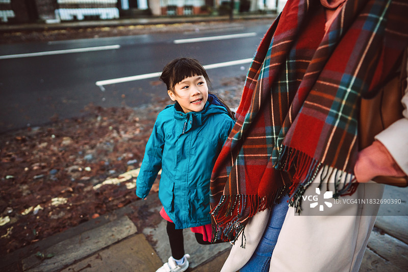 可爱开朗的女孩走在大街上和她的妈妈在一个小镇上探索图片素材