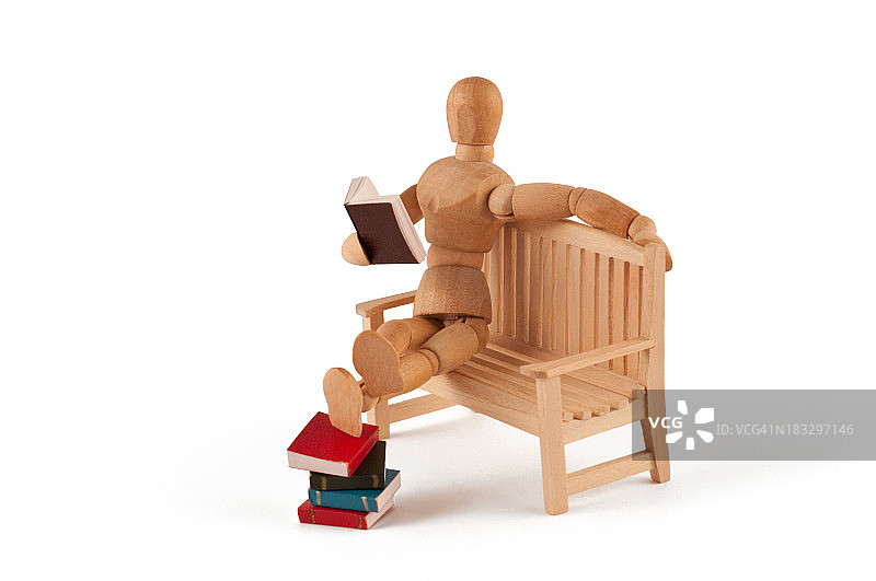 阅读人体模型放松在长凳上的脚上的书图片素材