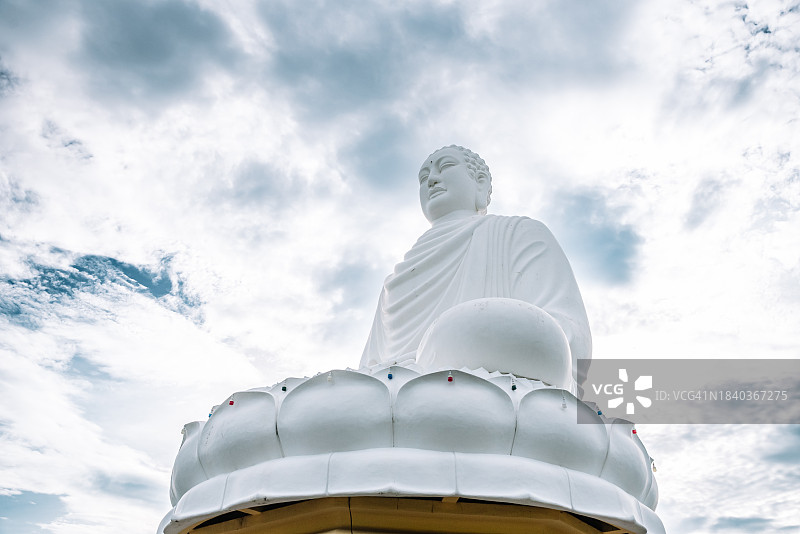 多云天空上的大佛雕像。越南芽庄的龙山塔寺。图片素材