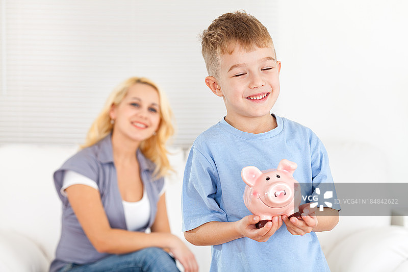 小男孩和他的妈妈把钱放进小猪存钱罐里图片素材